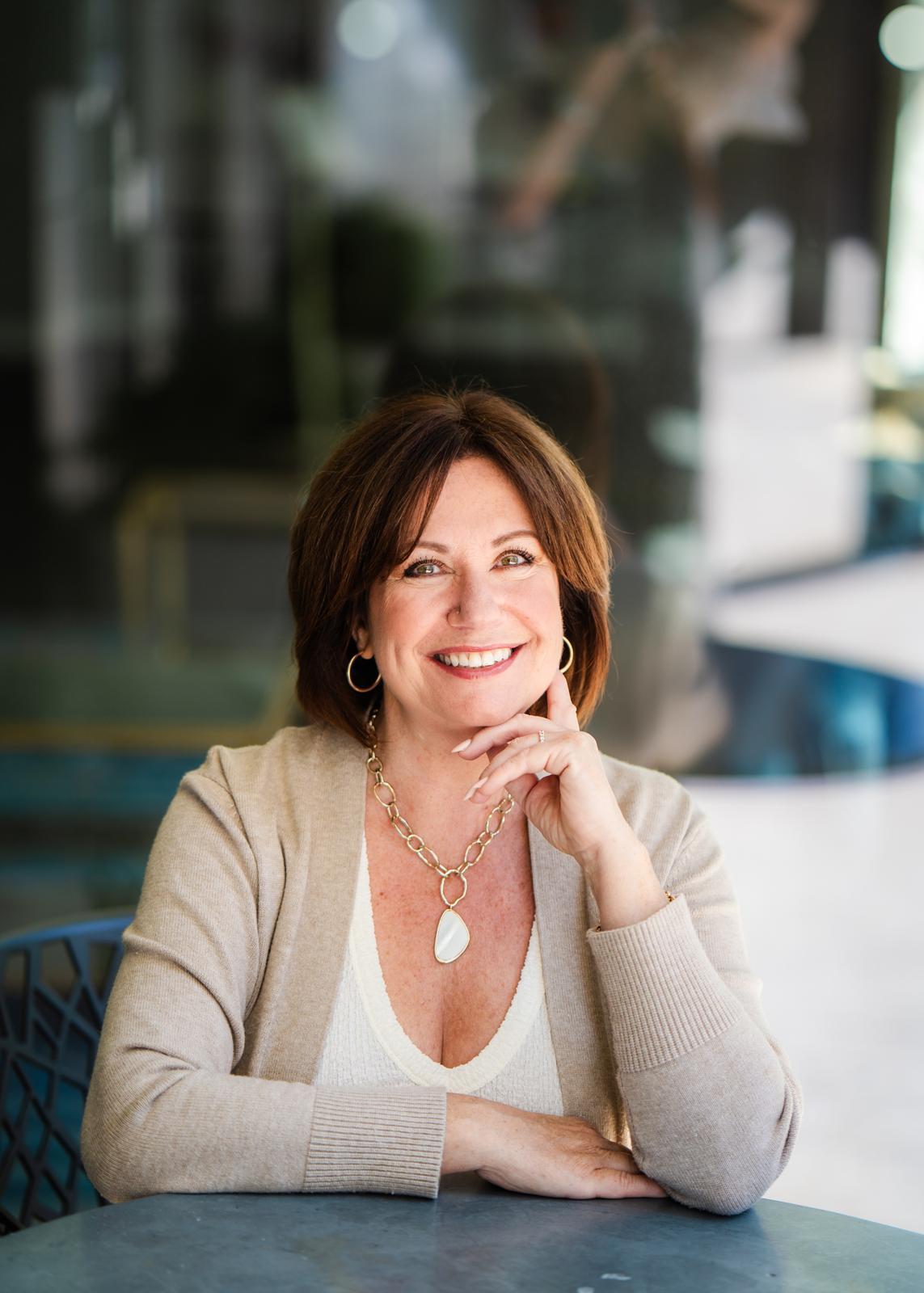 Nikki sitting in a café with her hand on her face smiling.