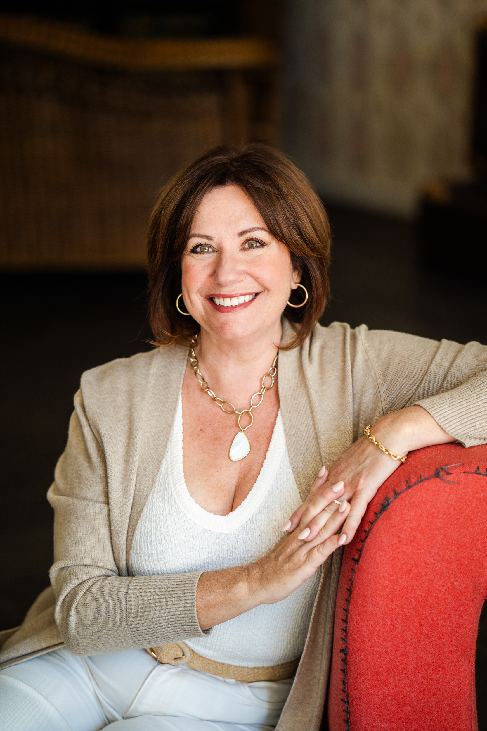 Nikki sitting on an orange sofa smiling.